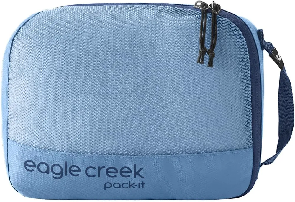 A set of three packing cubes packed with folded clothes beside an open carry-on bag