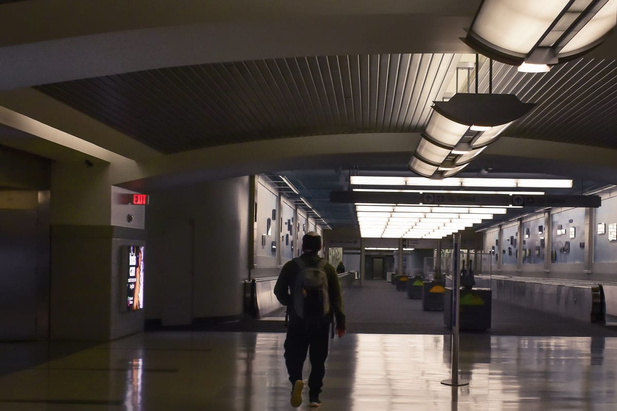 Traveller wearing a small backpack walking along a quiet airport corridor