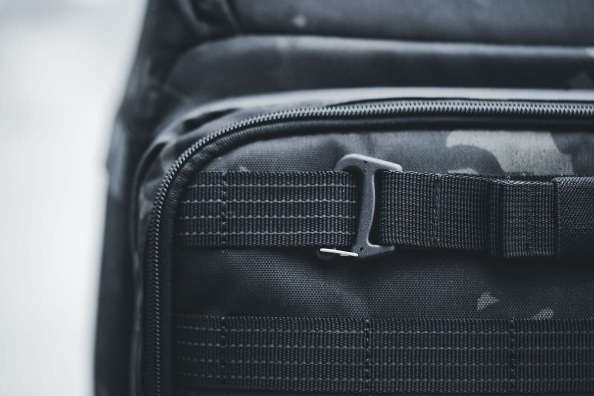 Close-up of a zip and a buckled strap on a black travel bag