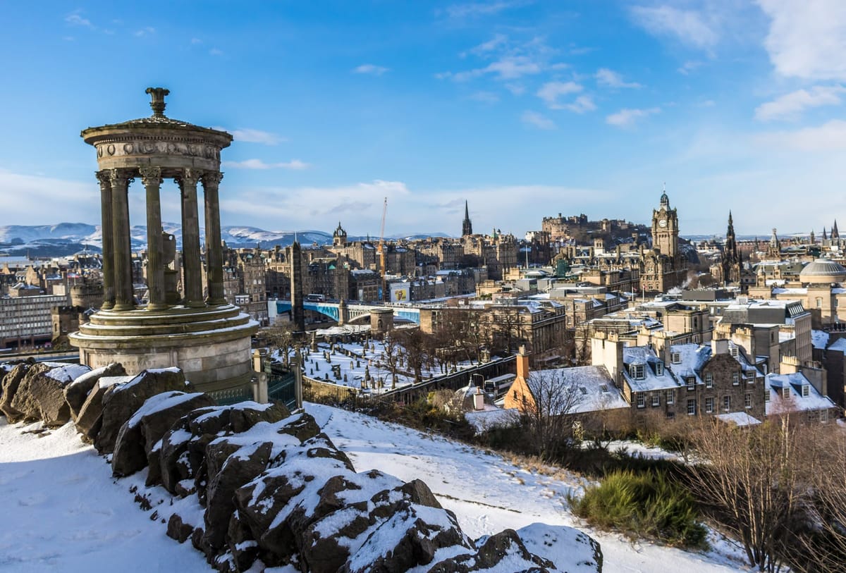 Snow on Calton Hill with the Dugald Stewart Monument and the Edinburgh Old Town skyline beyond