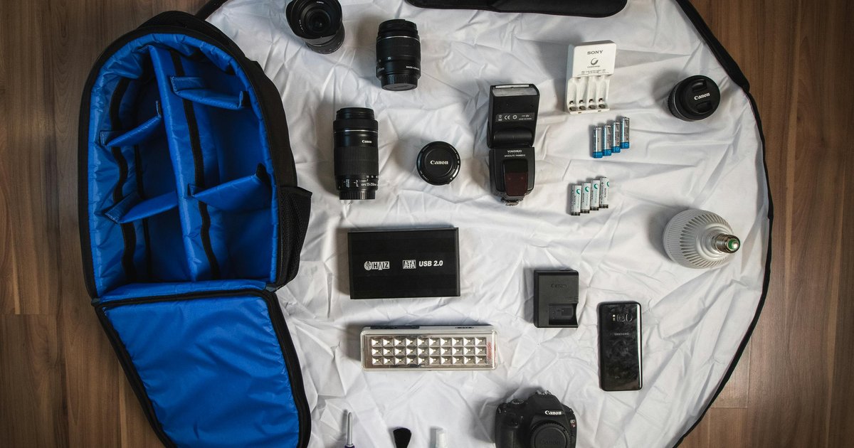 Overhead flatlay of a single carry-on backpack with travel essentials laid out beside it