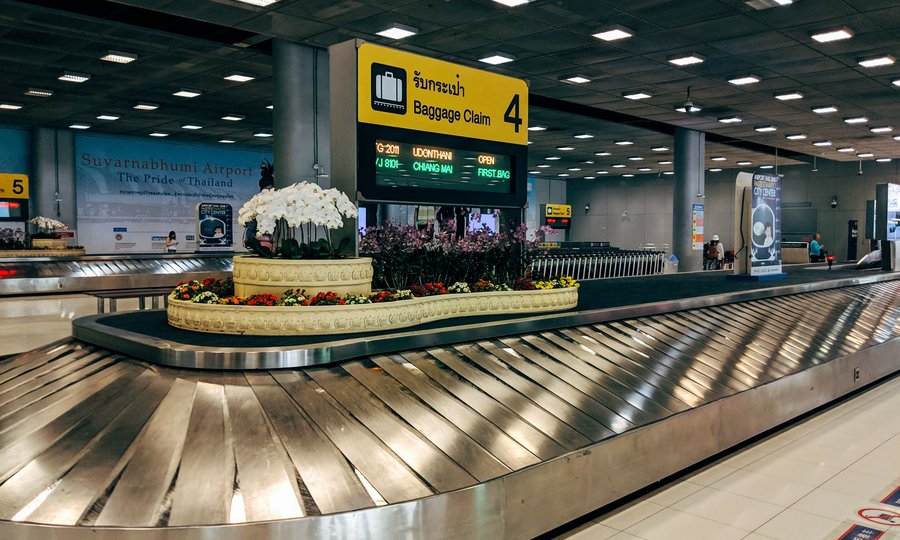 Airport concourse with travellers and carry-on bags, wide shot