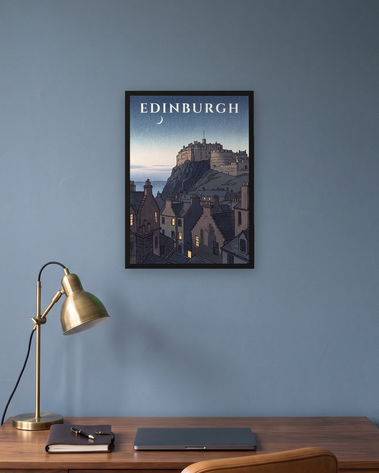 Edinburgh Castle at Dusk travel print in a black frame on a blue wall above a desk with a brass lamp