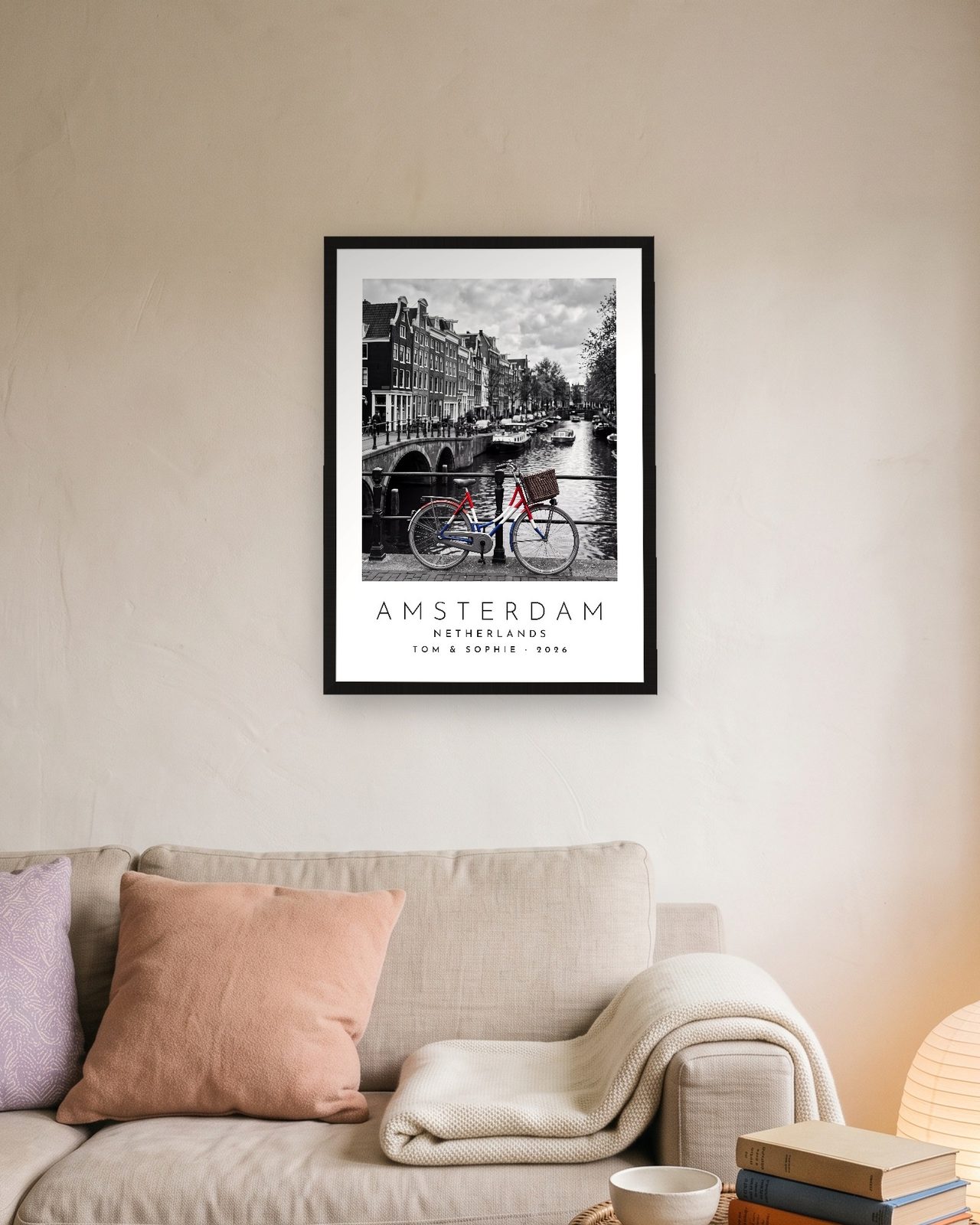 Our Trip Amsterdam print: black frame A3 above a linen sofa, personalised TOM & SOPHIE · 2026