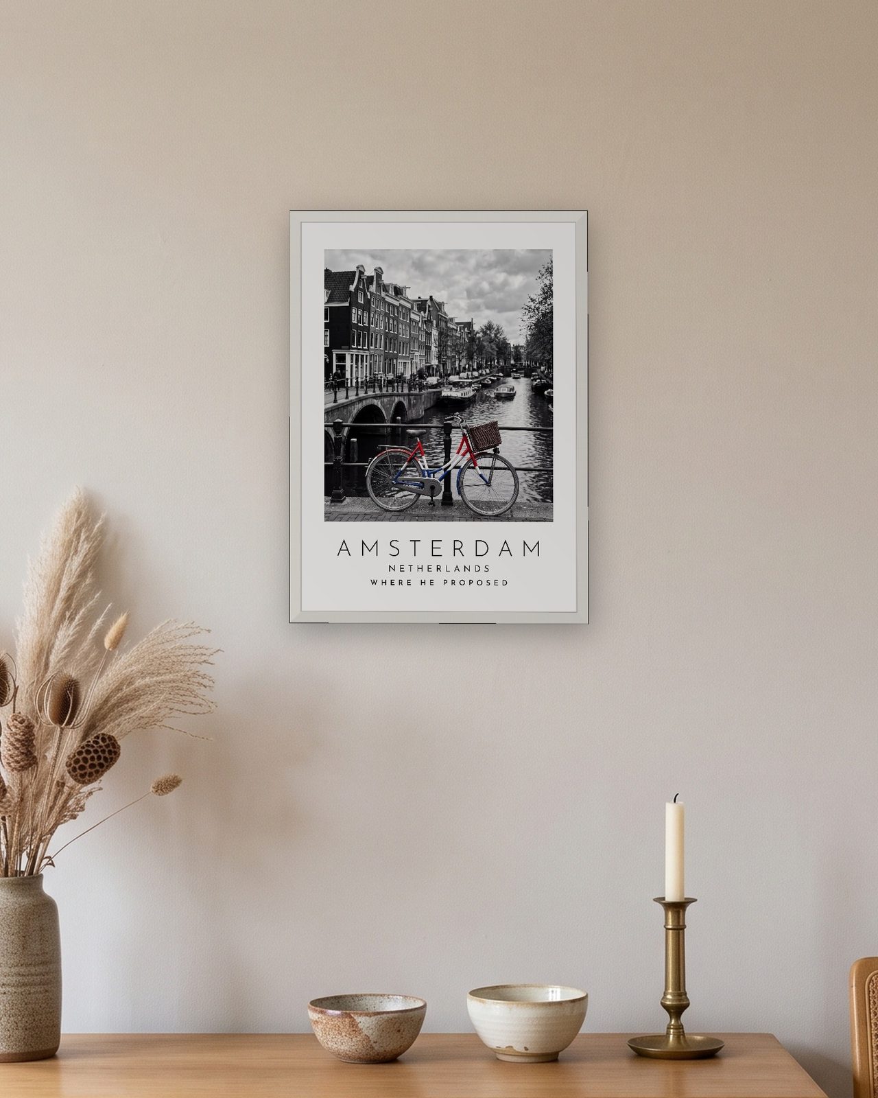 Our Trip Amsterdam print: white frame A3 above an oak sideboard, personalised WHERE HE PROPOSED
