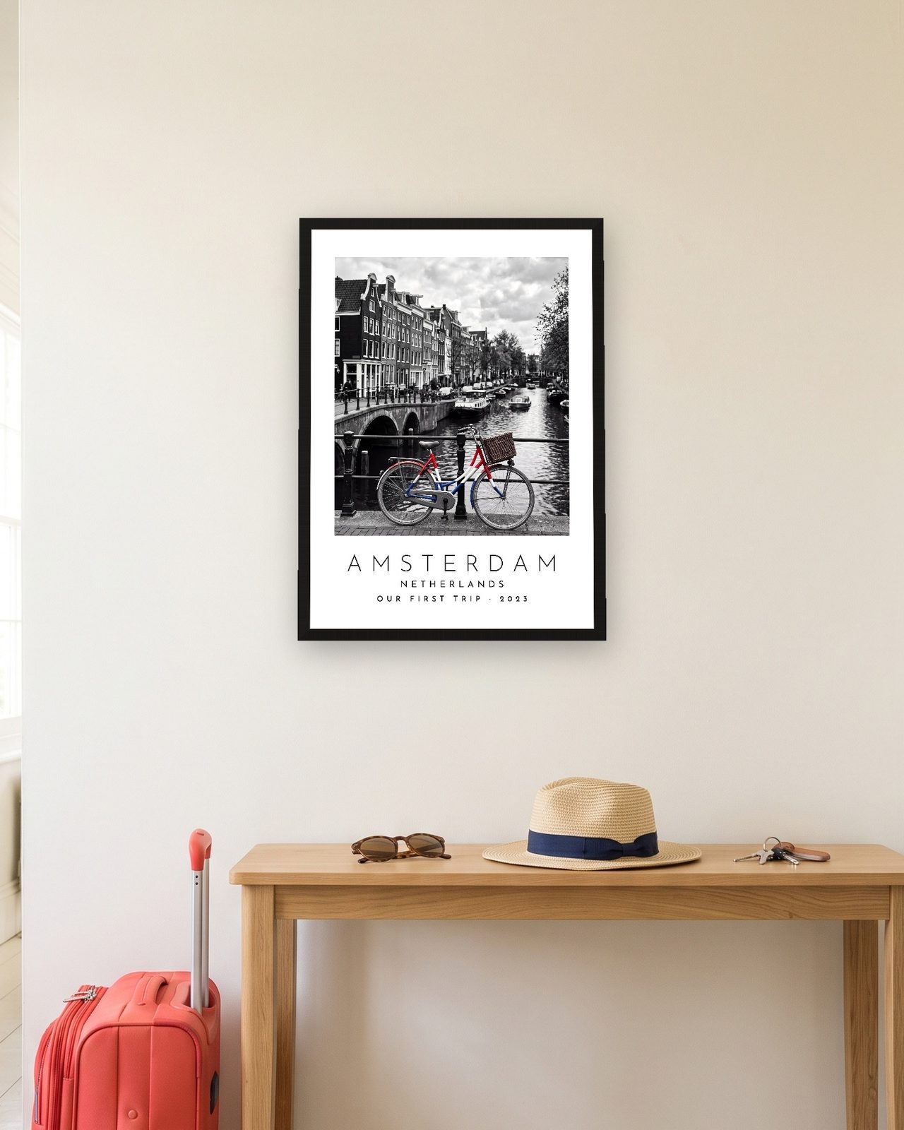 Our Trip Amsterdam print: black frame A3 in a hallway with a packed suitcase, personalised OUR FIRST TRIP · 2023