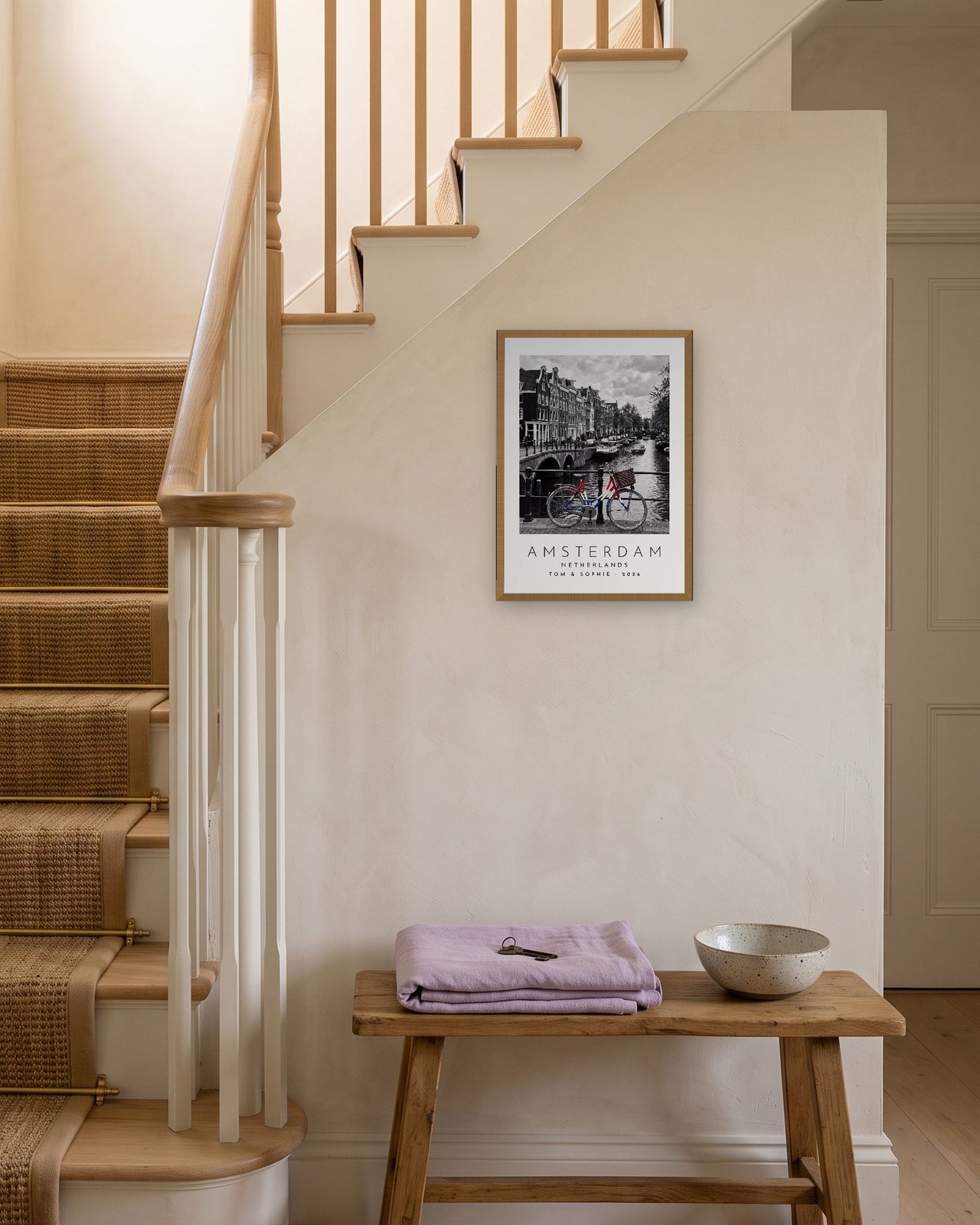 Our Trip Amsterdam print: natural oak frame A3 on a staircase wall, personalised TOM & SOPHIE · 2026
