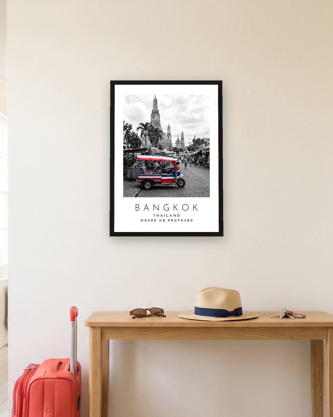 Our Trip Bangkok print: black frame A3 in a hallway with a packed suitcase, personalised WHERE HE PROPOSED