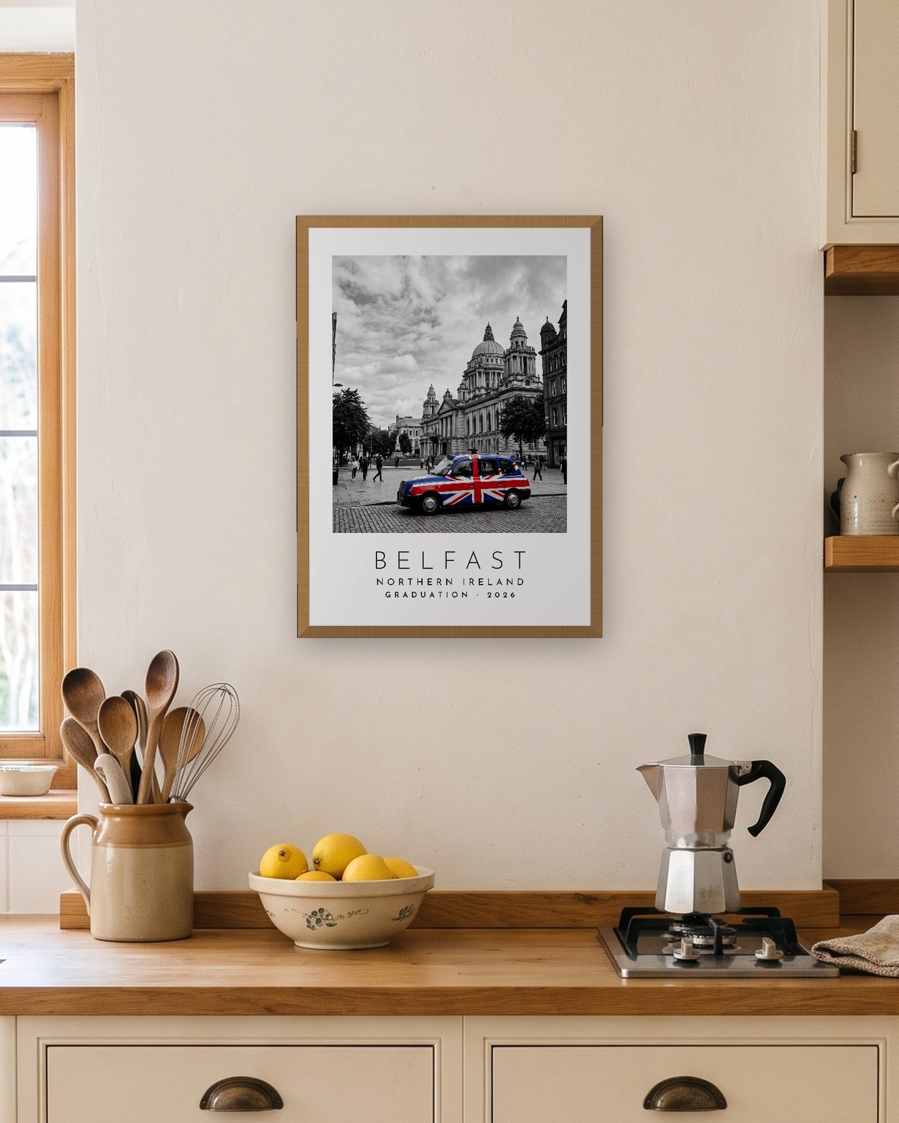 Our Trip Belfast print: natural oak frame A3 in a bright kitchen, personalised GRADUATION · 2026