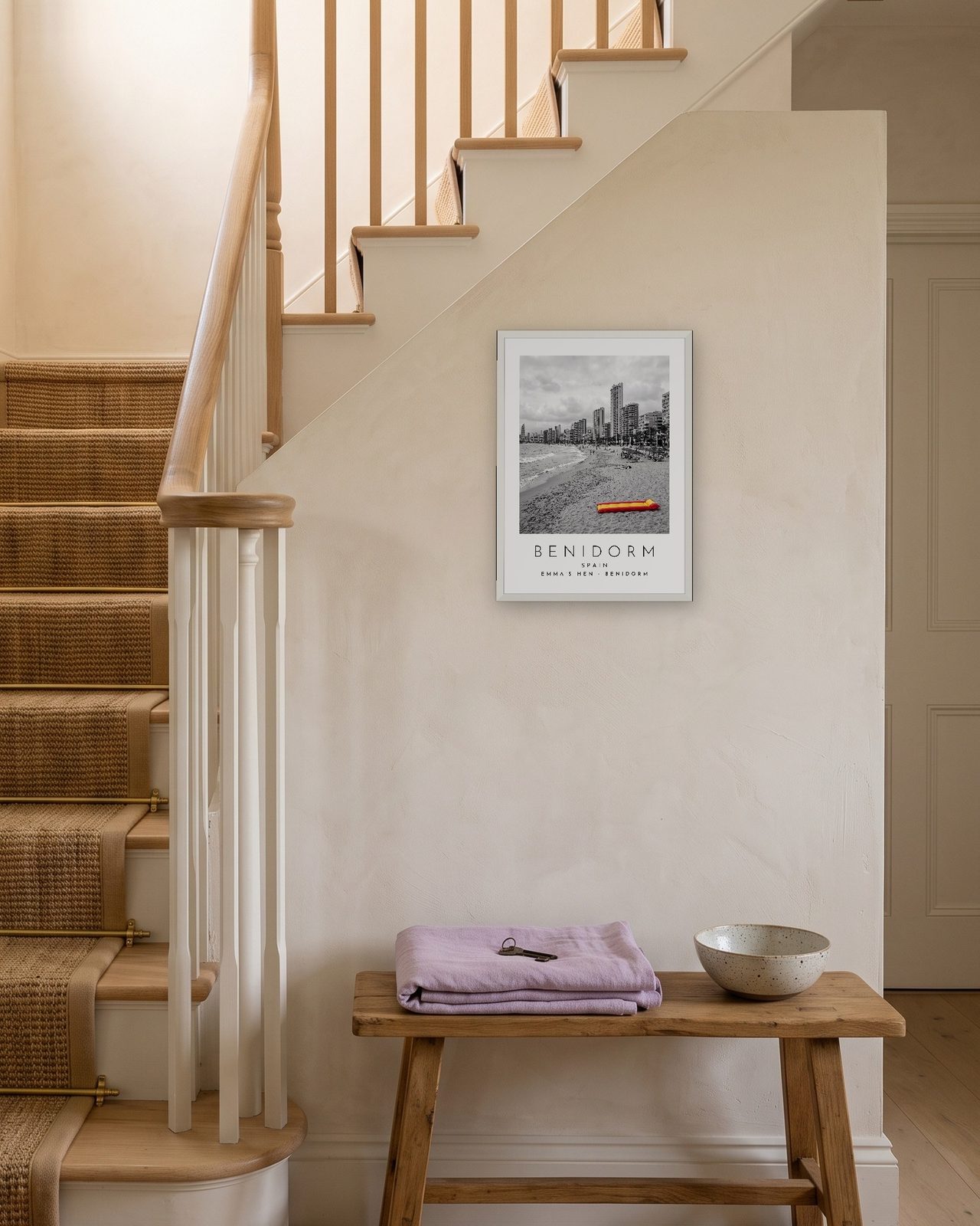Our Trip Benidorm print: white frame A3 on a staircase wall, personalised EMMA'S HEN · BENIDORM