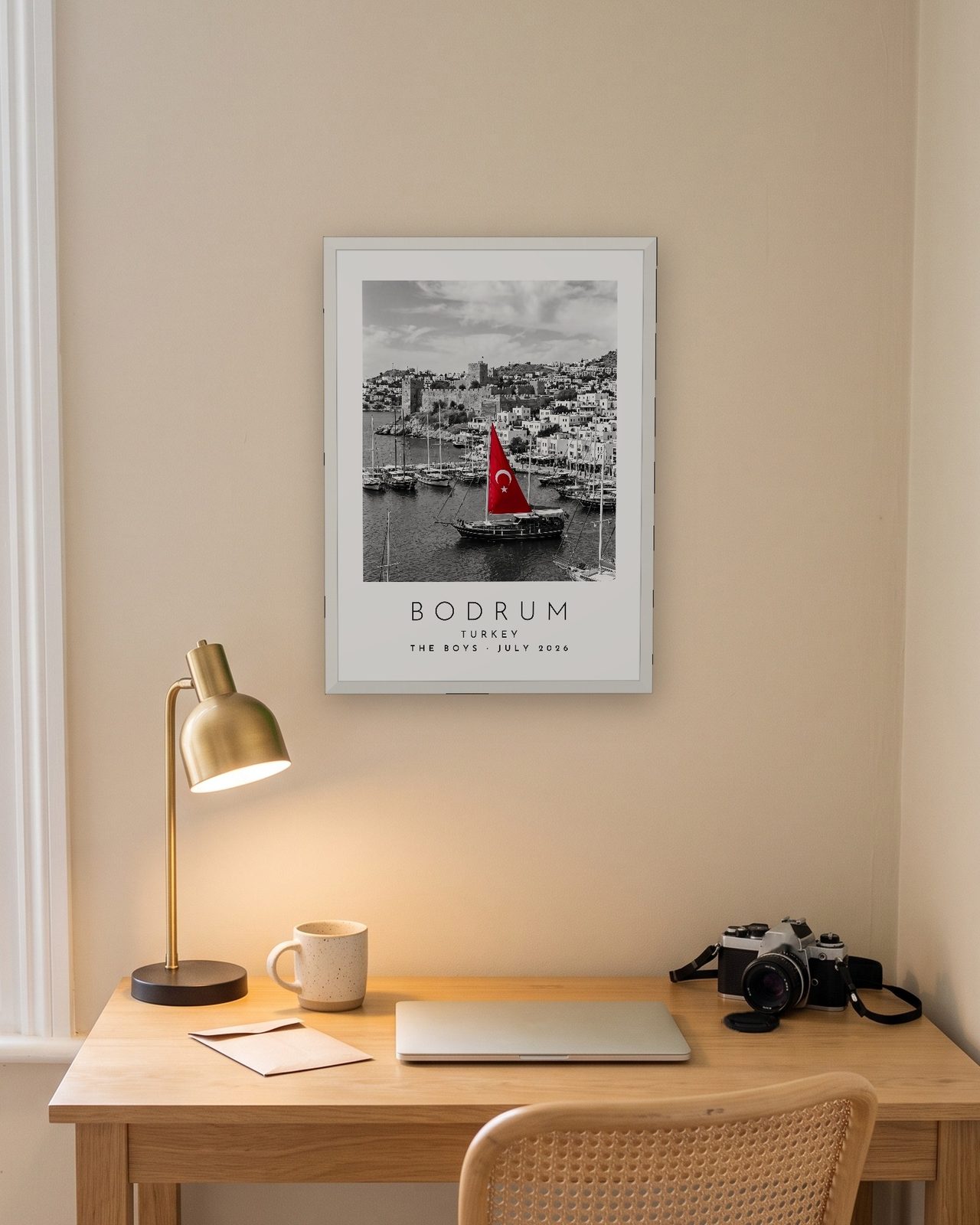 Our Trip Bodrum print: white frame A3 above a home office desk, personalised THE BOYS · JULY 2026