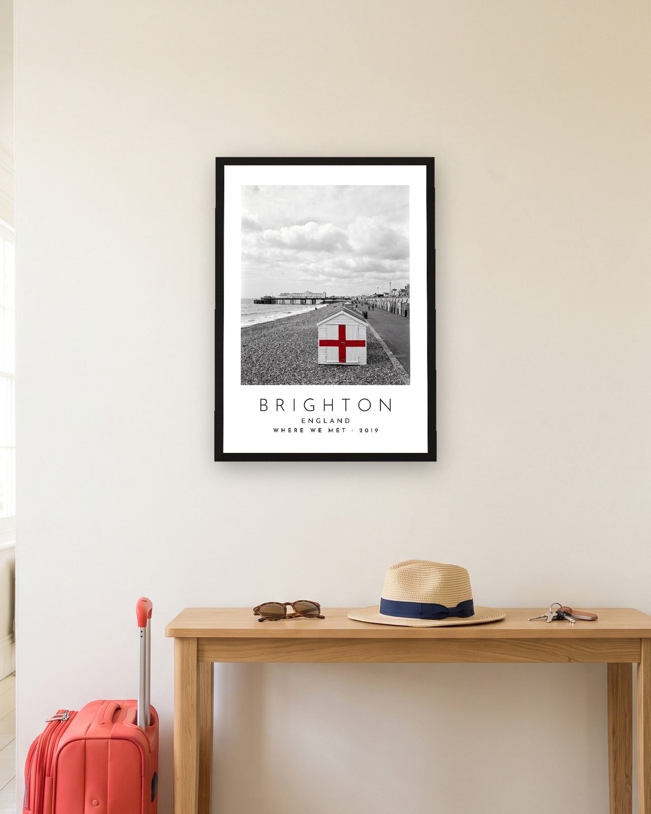 Our Trip Brighton print: black frame A3 in a hallway with a packed suitcase, personalised WHERE WE MET · 2019