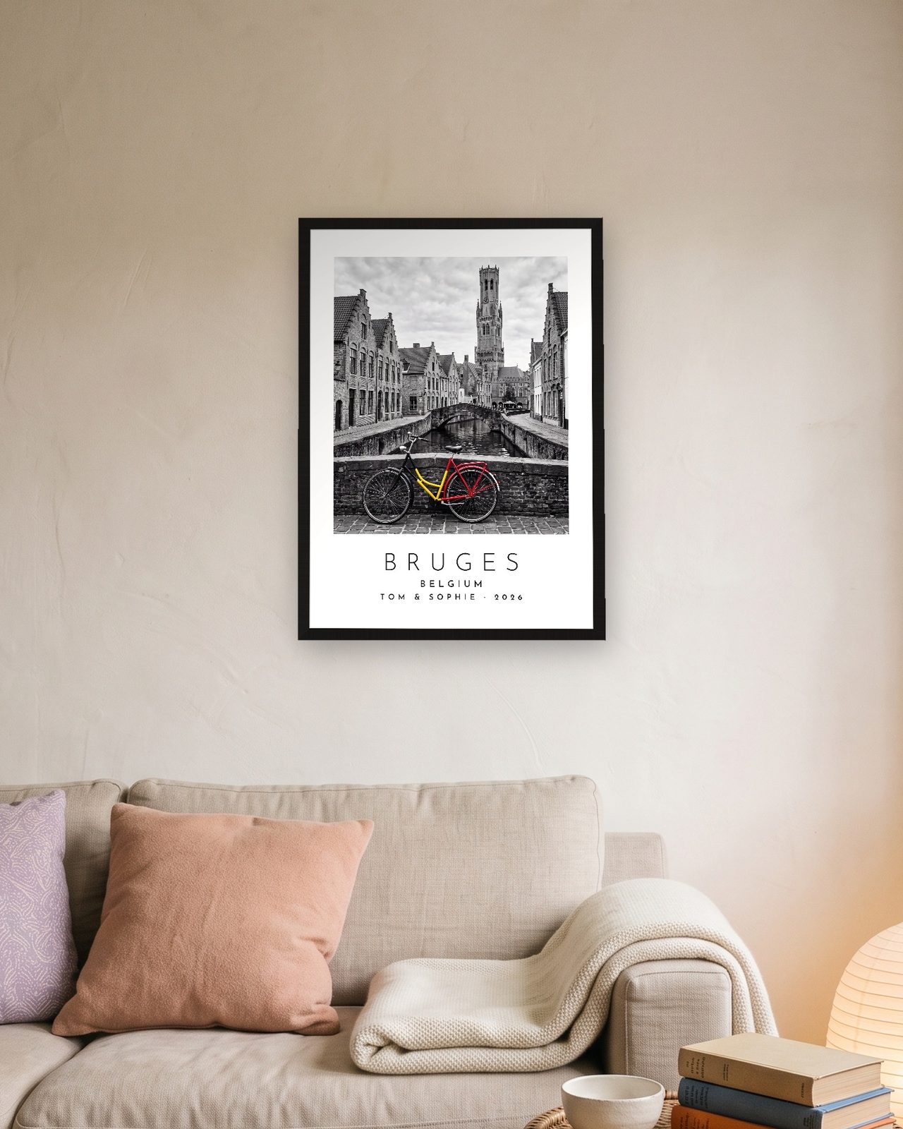 Our Trip Bruges print: black frame A3 above a linen sofa, personalised TOM & SOPHIE · 2026