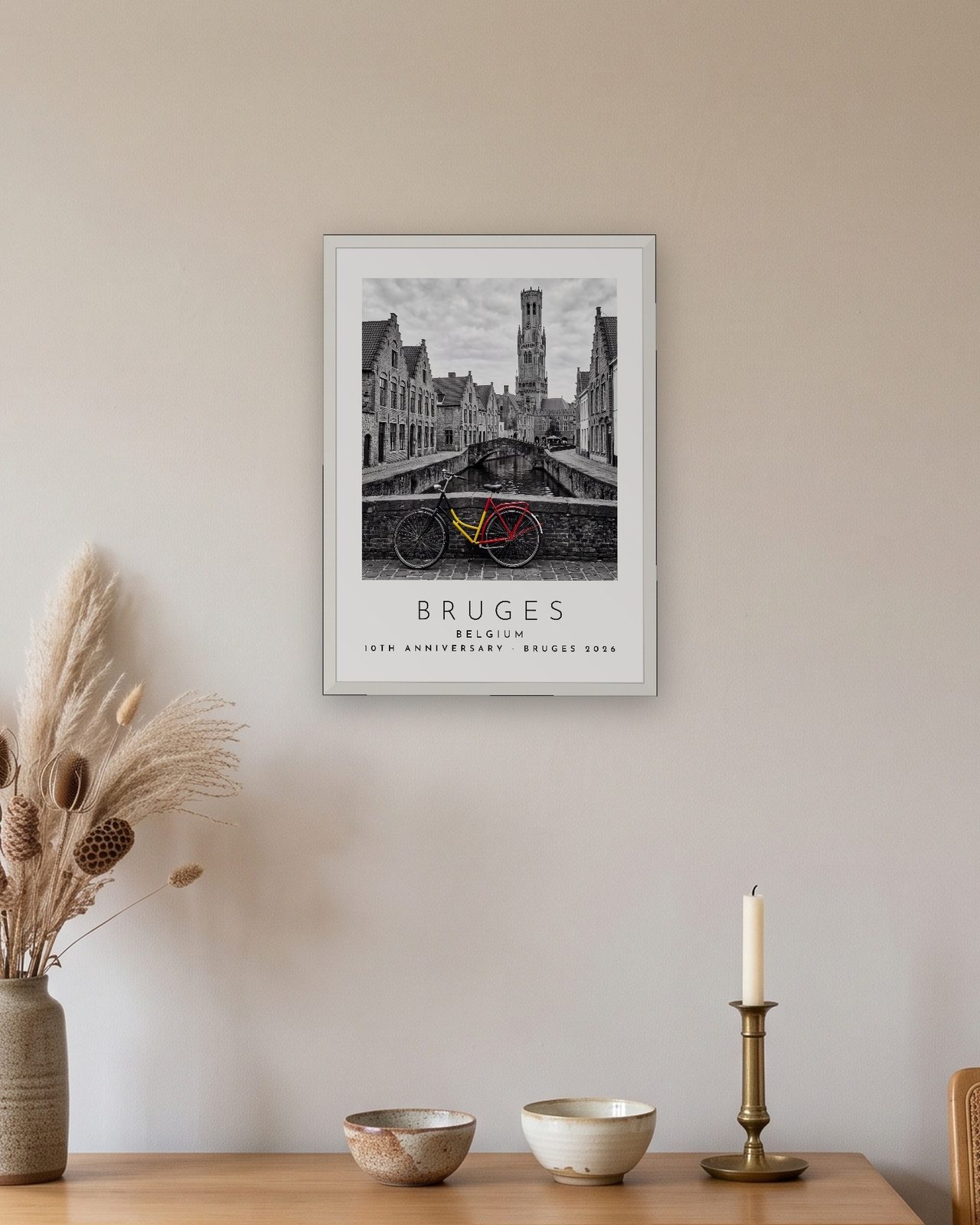 Our Trip Bruges print: white frame A3 above an oak sideboard, personalised 10TH ANNIVERSARY · BRUGES 2026