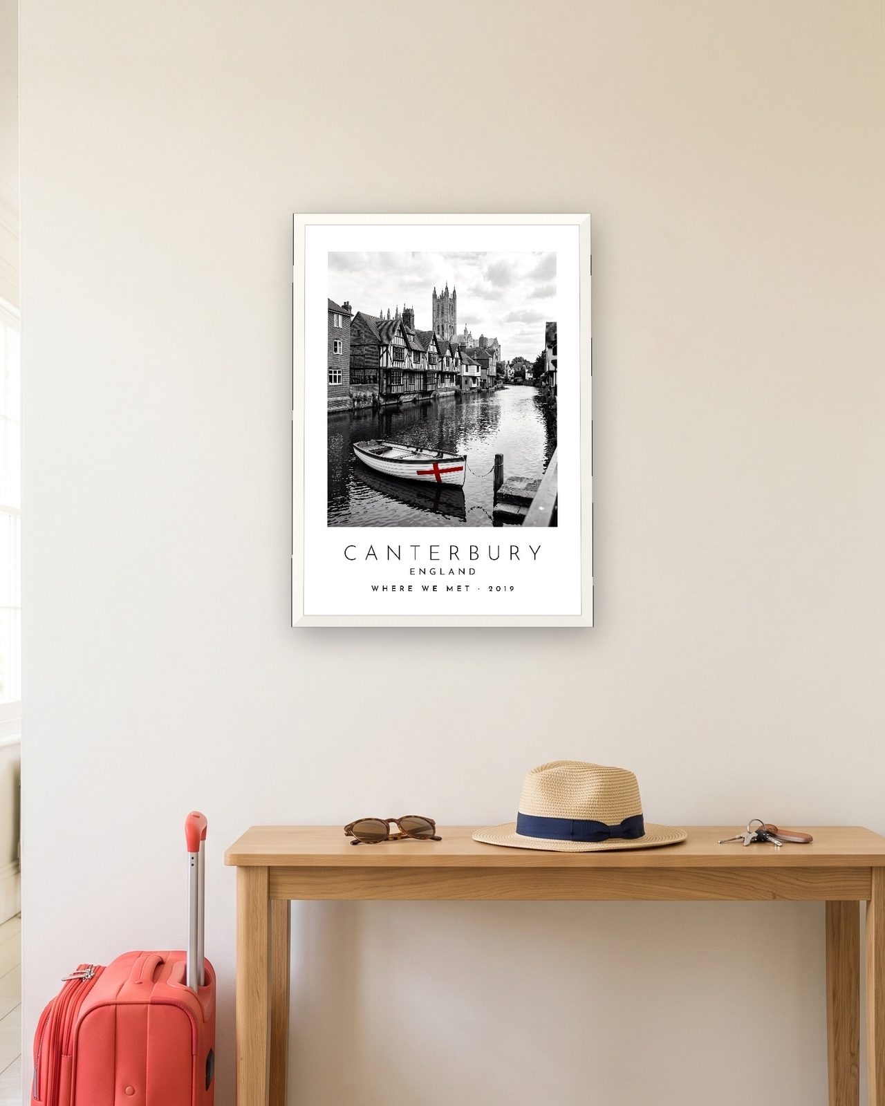 Our Trip Canterbury print: white frame A3 in a hallway with a packed suitcase, personalised WHERE WE MET · 2019