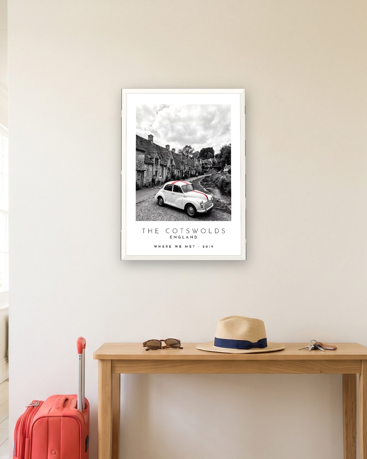 Our Trip The Cotswolds print: white frame A3 in a hallway with a packed suitcase, personalised WHERE WE MET · 2019