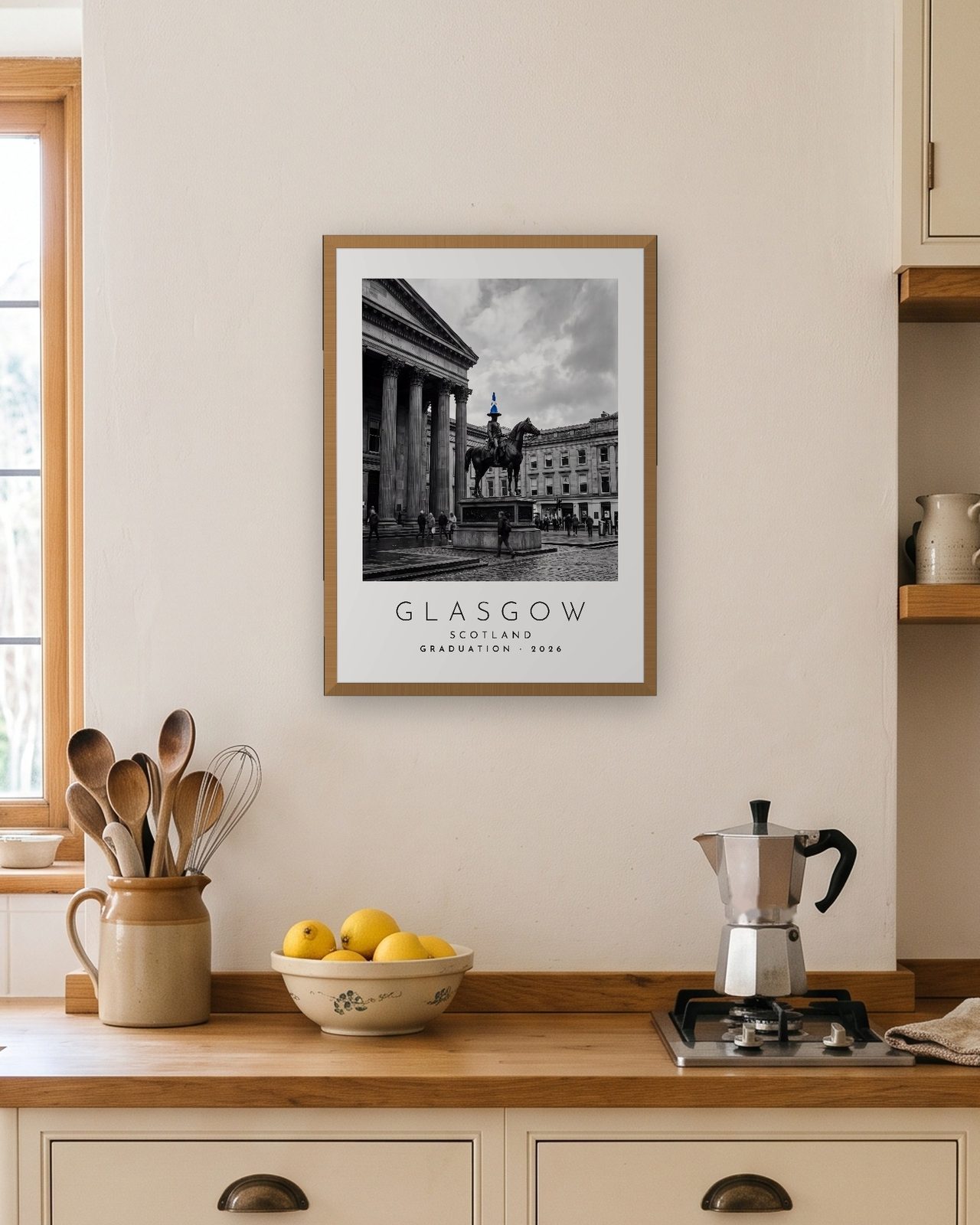 Our Trip Glasgow print: natural oak frame A3 in a bright kitchen, personalised GRADUATION · 2026