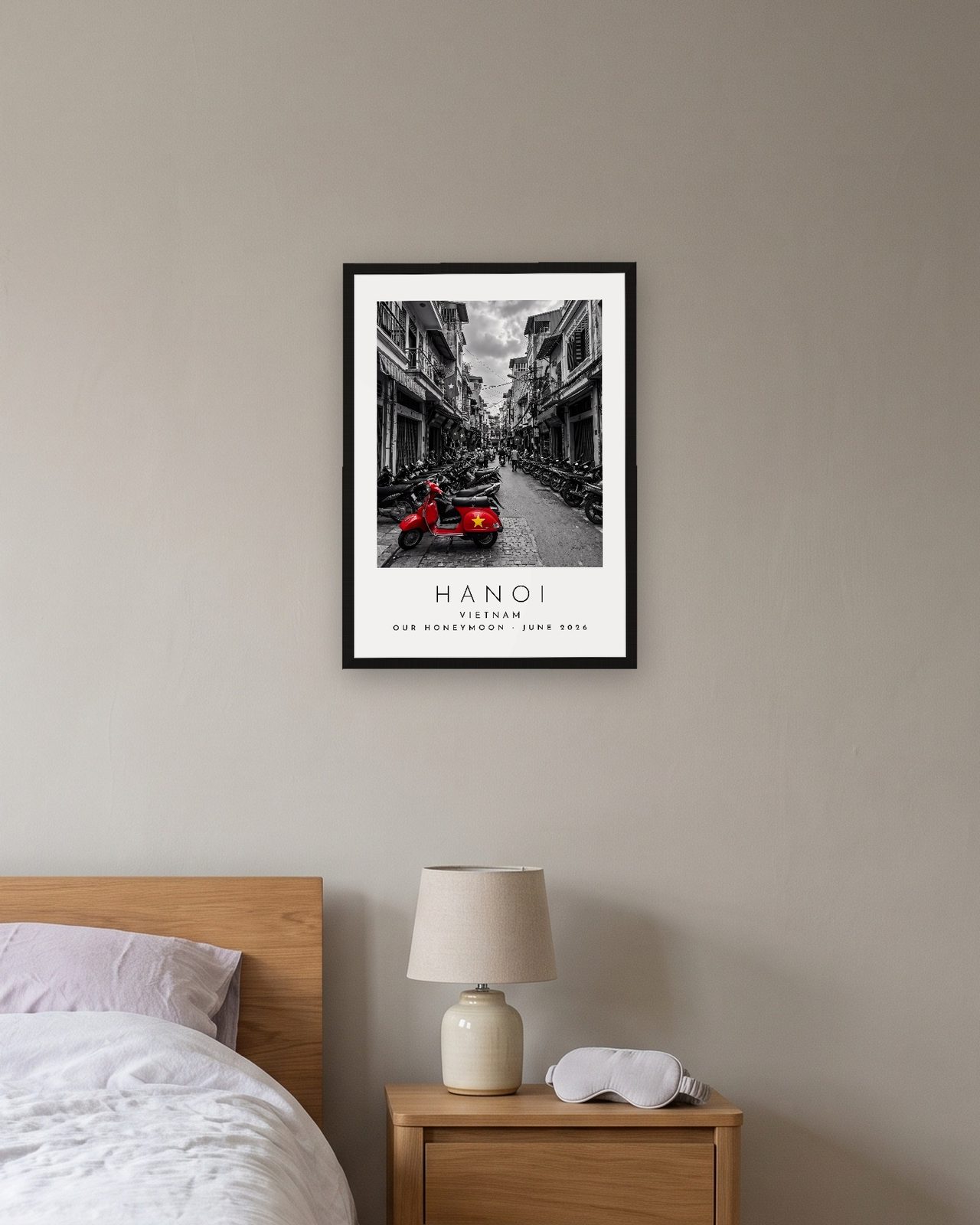 Our Trip Hanoi print: black frame A3 above a bedside table, personalised OUR HONEYMOON · JUNE 2026