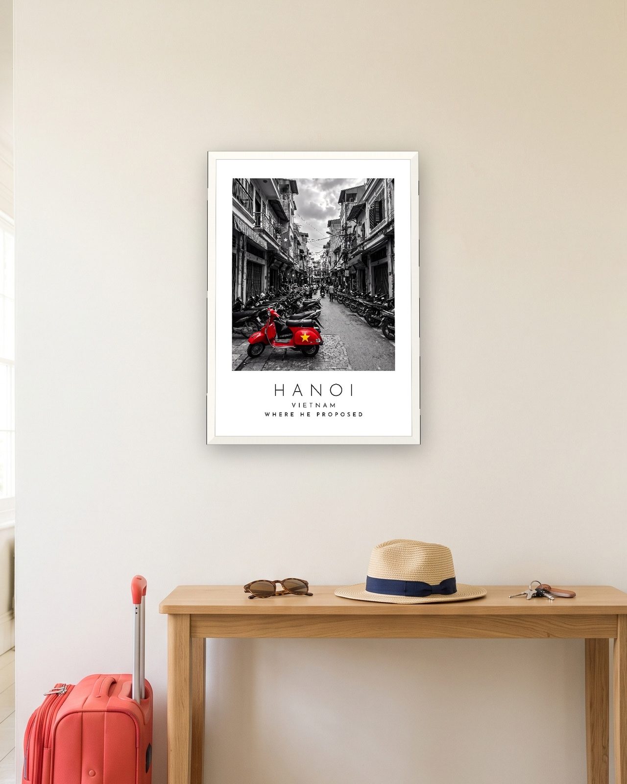 Our Trip Hanoi print: white frame A3 in a hallway with a packed suitcase, personalised WHERE HE PROPOSED