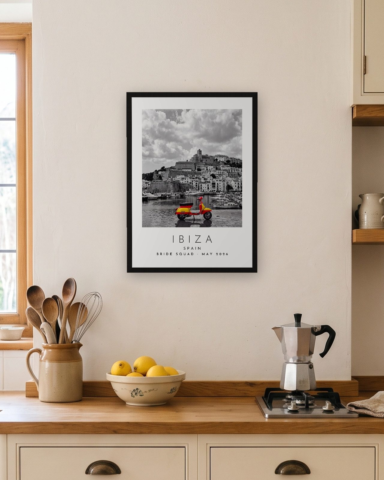 Our Trip Ibiza print: black frame A3 in a bright kitchen, personalised BRIDE SQUAD · MAY 2026