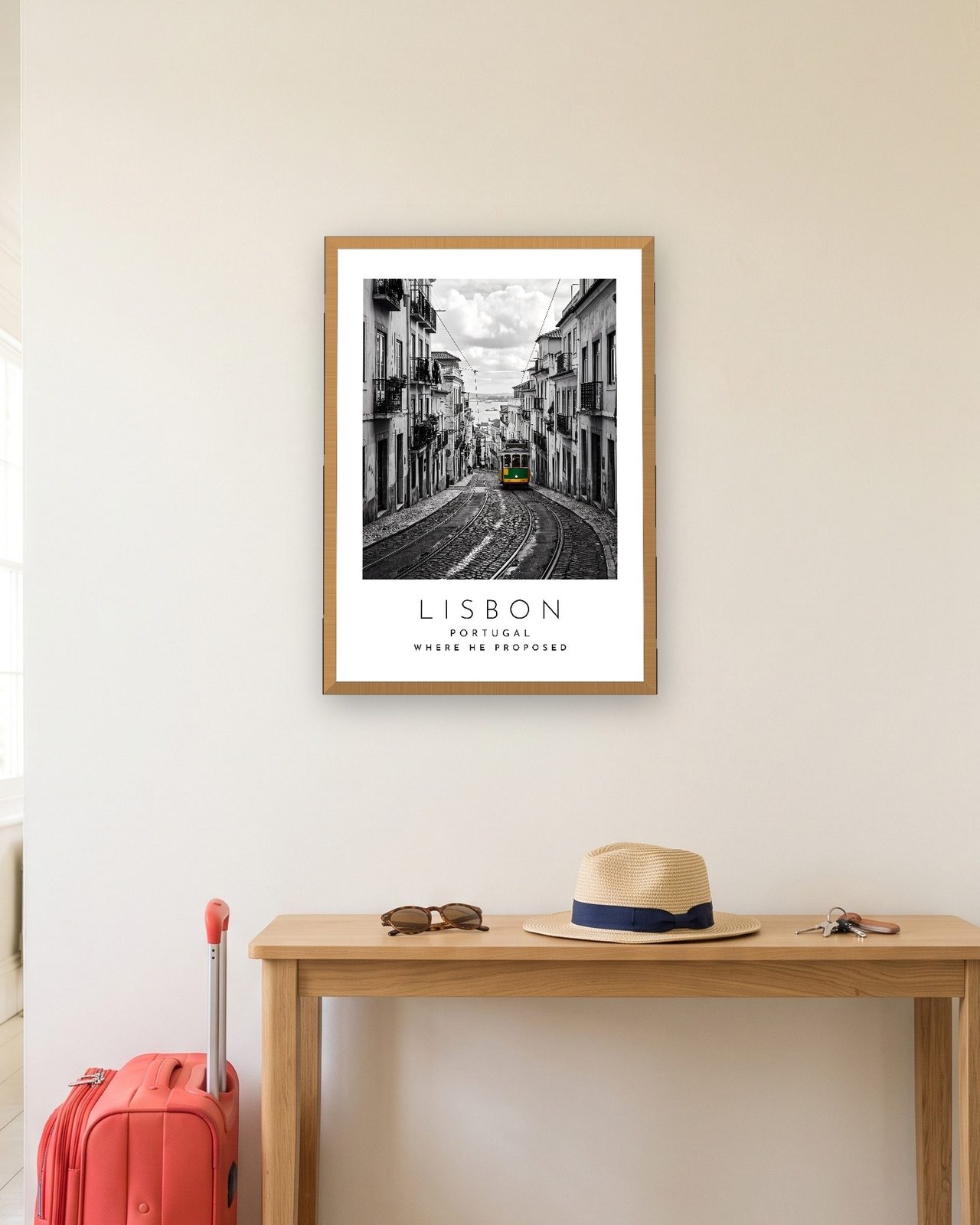 Our Trip Lisbon print: natural oak frame A3 in a hallway with a packed suitcase, personalised WHERE HE PROPOSED