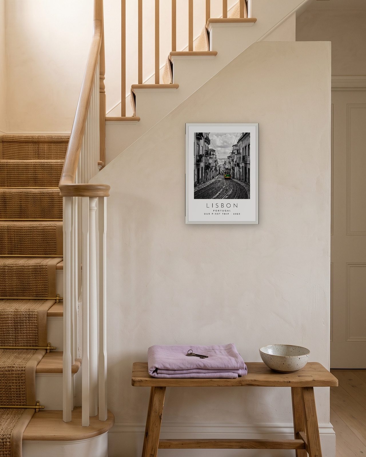 Our Trip Lisbon print: white frame A3 on a staircase wall, personalised OUR FIRST TRIP · 2023