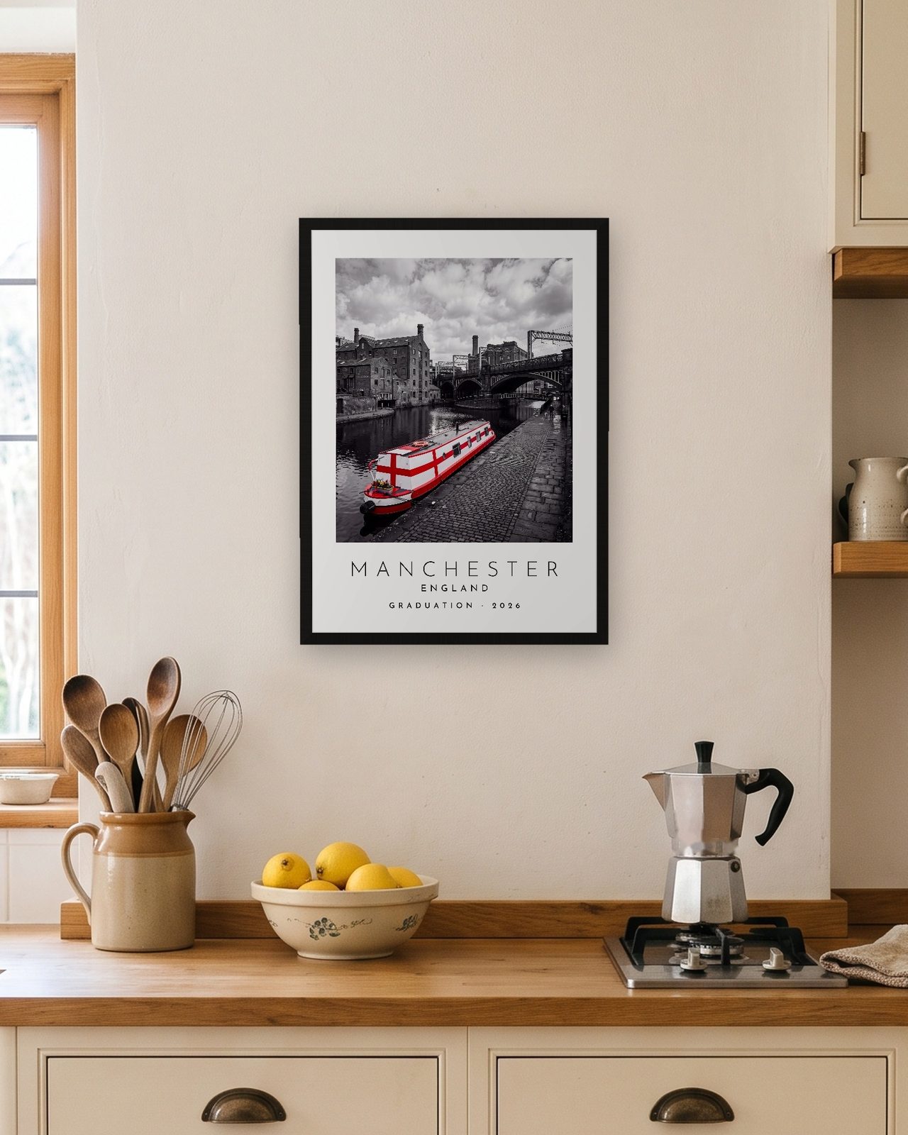 Our Trip Manchester print: black frame A3 in a bright kitchen, personalised GRADUATION · 2026