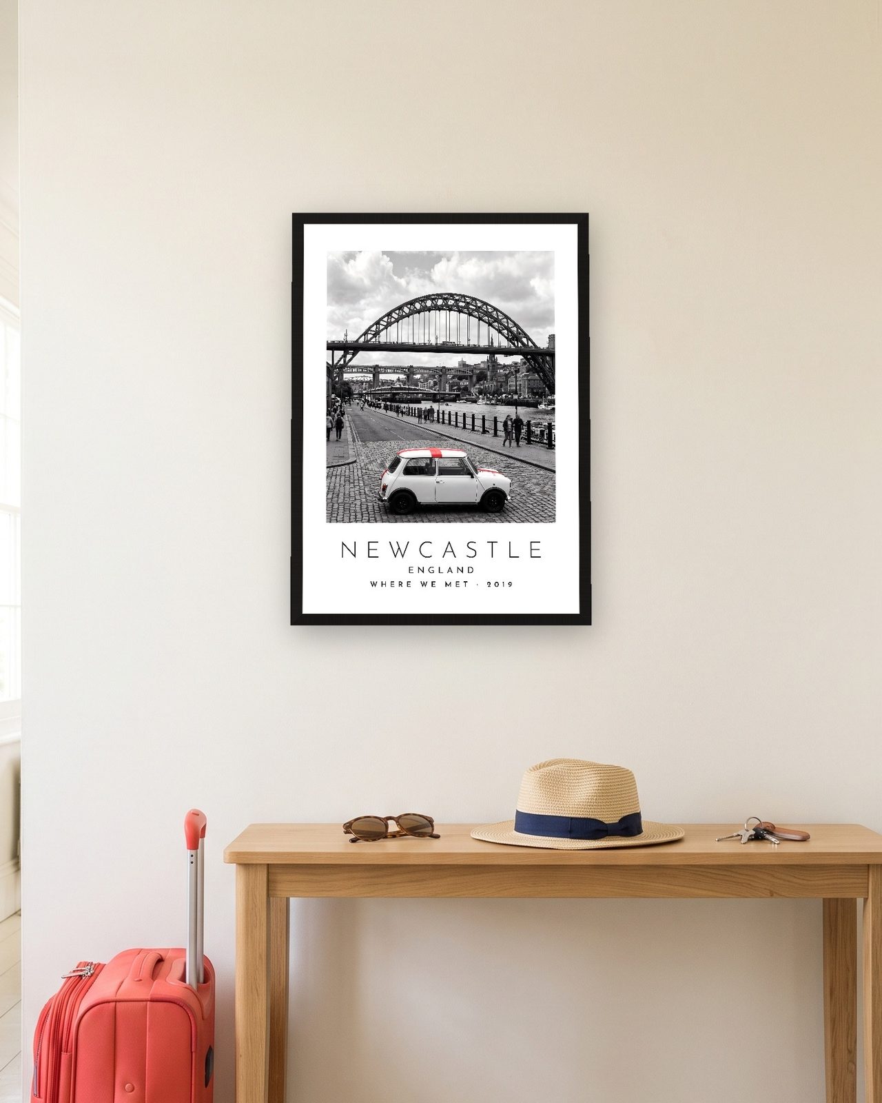 Our Trip Newcastle print: black frame A3 in a hallway with a packed suitcase, personalised WHERE WE MET · 2019