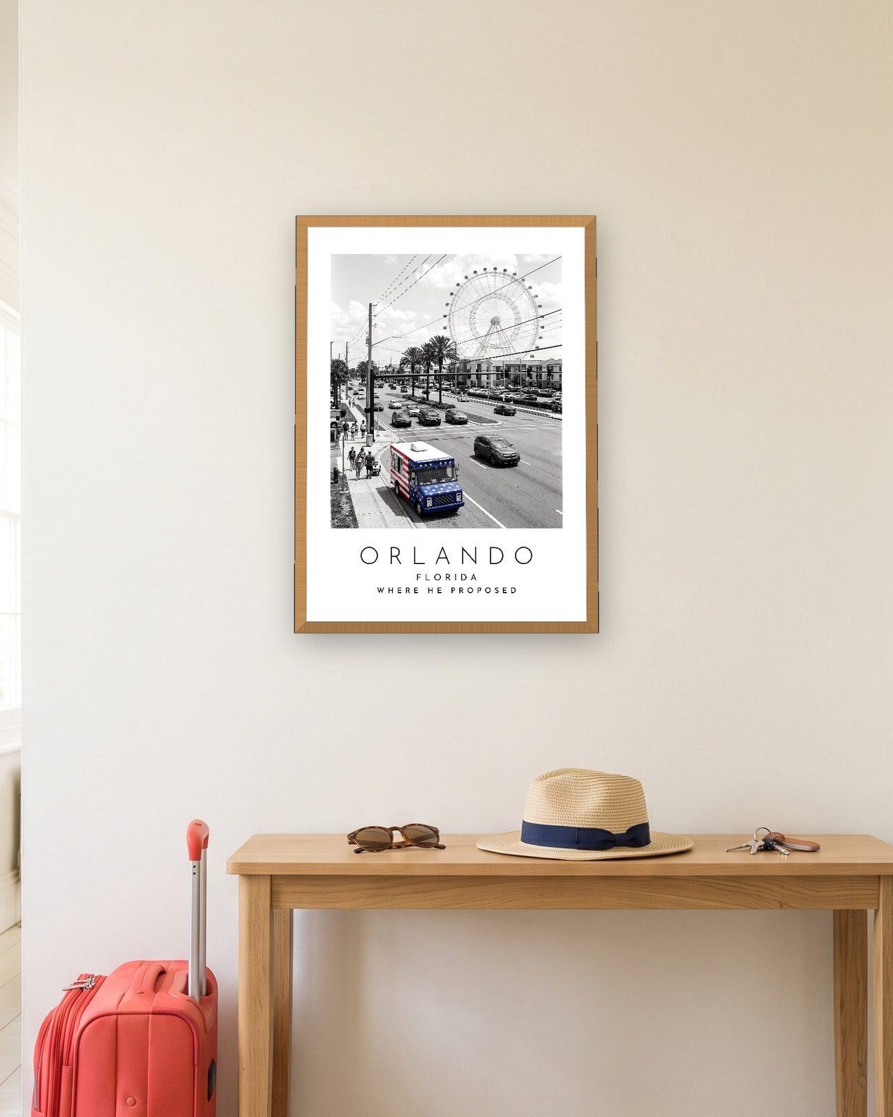 Our Trip Orlando print: natural oak frame A3 in a hallway with a packed suitcase, personalised WHERE HE PROPOSED