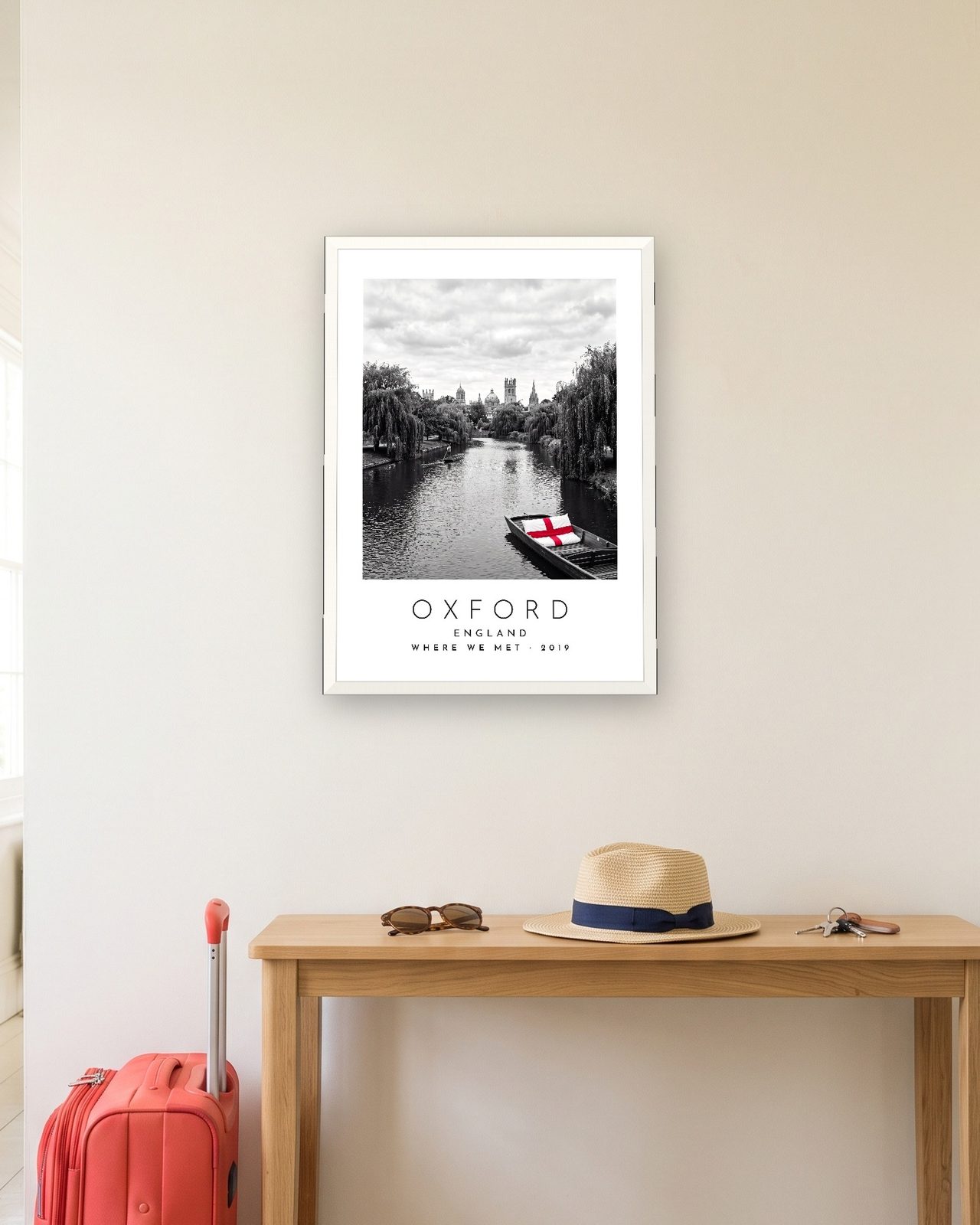 Our Trip Oxford print: white frame A3 in a hallway with a packed suitcase, personalised WHERE WE MET · 2019