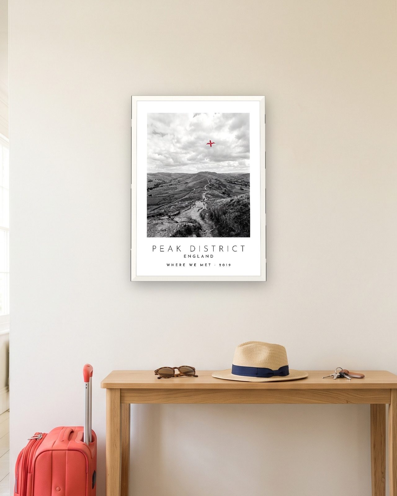 Our Trip Peak District print: white frame A3 in a hallway with a packed suitcase, personalised WHERE WE MET · 2019