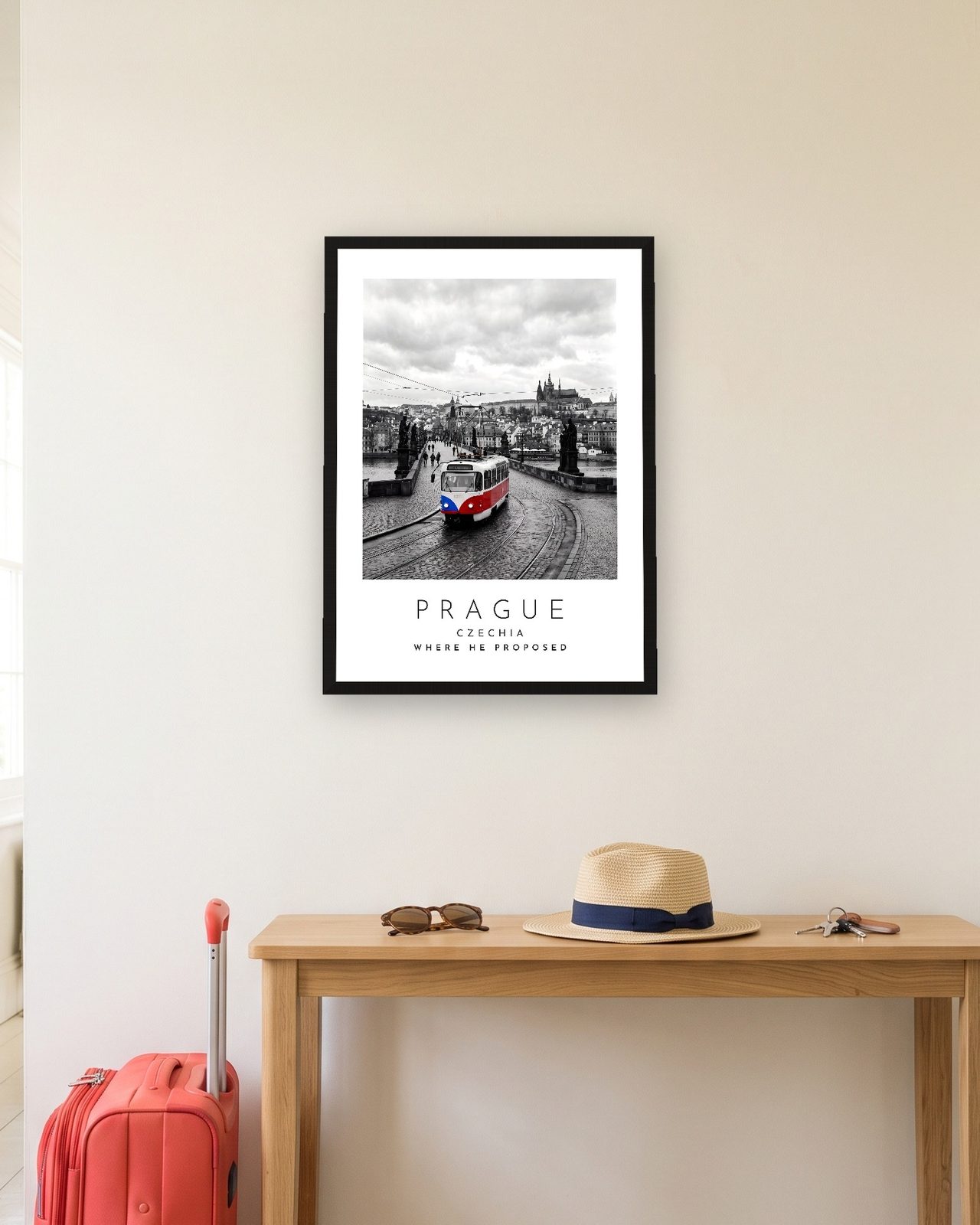 Our Trip Prague print: black frame A3 in a hallway with a packed suitcase, personalised WHERE HE PROPOSED