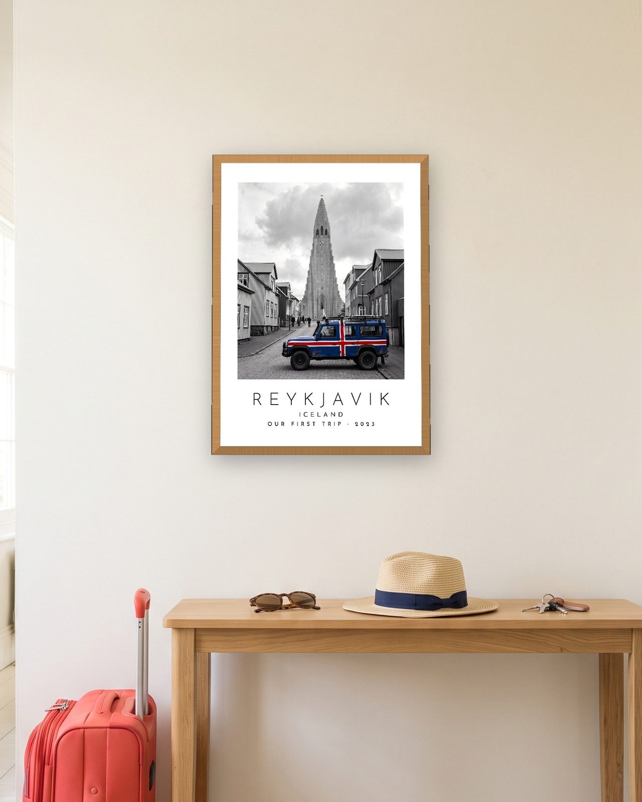 Our Trip Reykjavik print: natural oak frame A3 in a hallway with a packed suitcase, personalised OUR FIRST TRIP · 2023