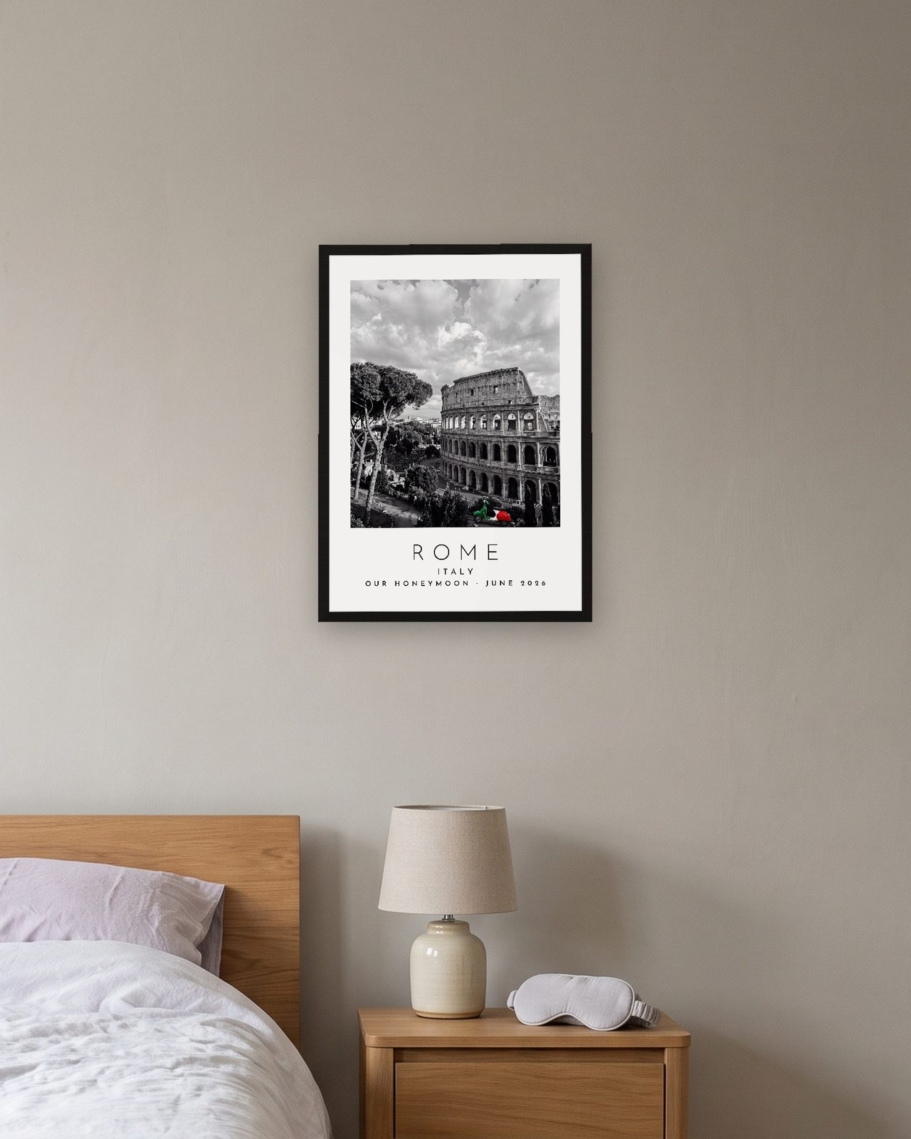 Our Trip Rome print: black frame A3 above a bedside table, personalised OUR HONEYMOON · JUNE 2026