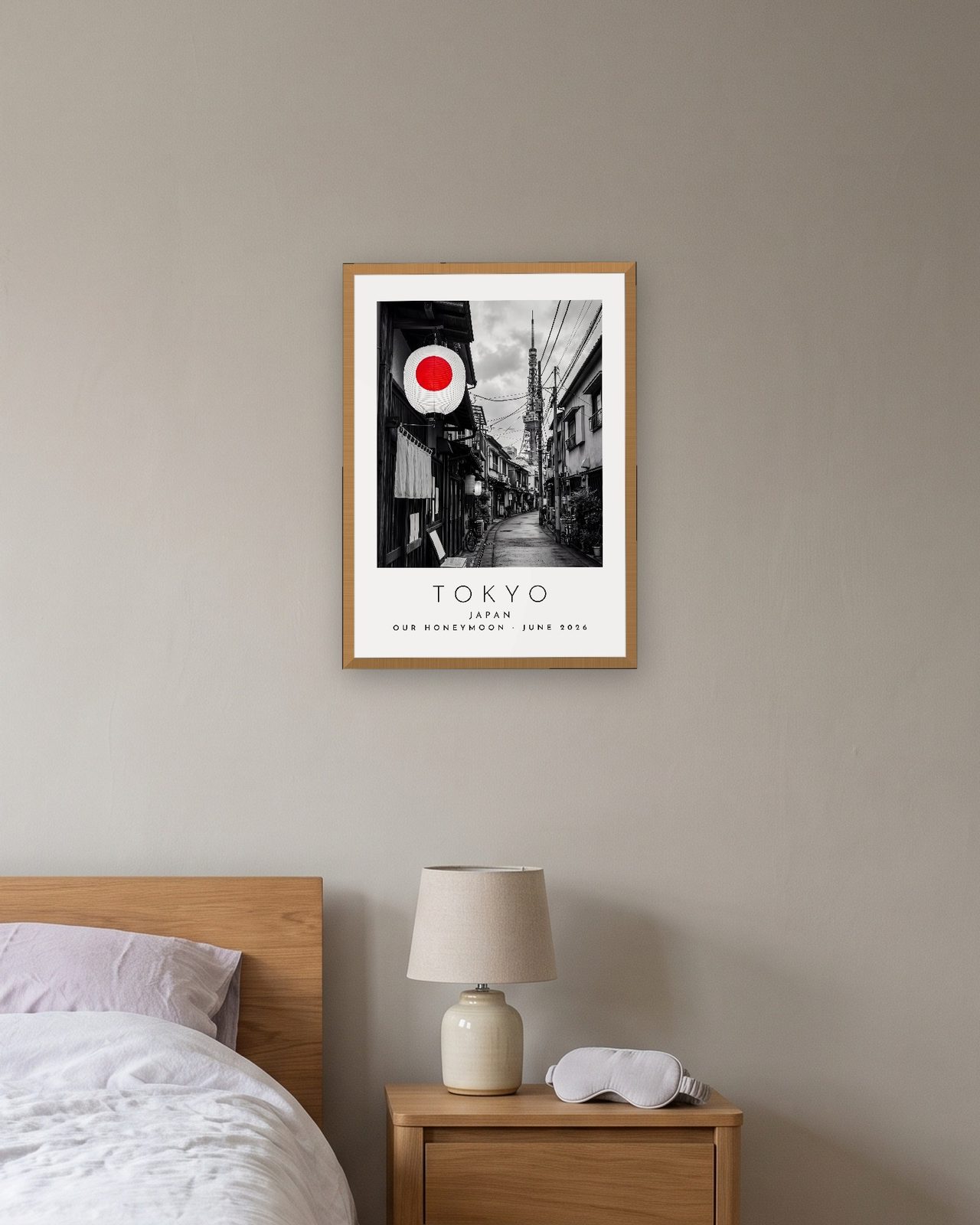 Our Trip Tokyo print: natural oak frame A3 above a bedside table, personalised OUR HONEYMOON · JUNE 2026