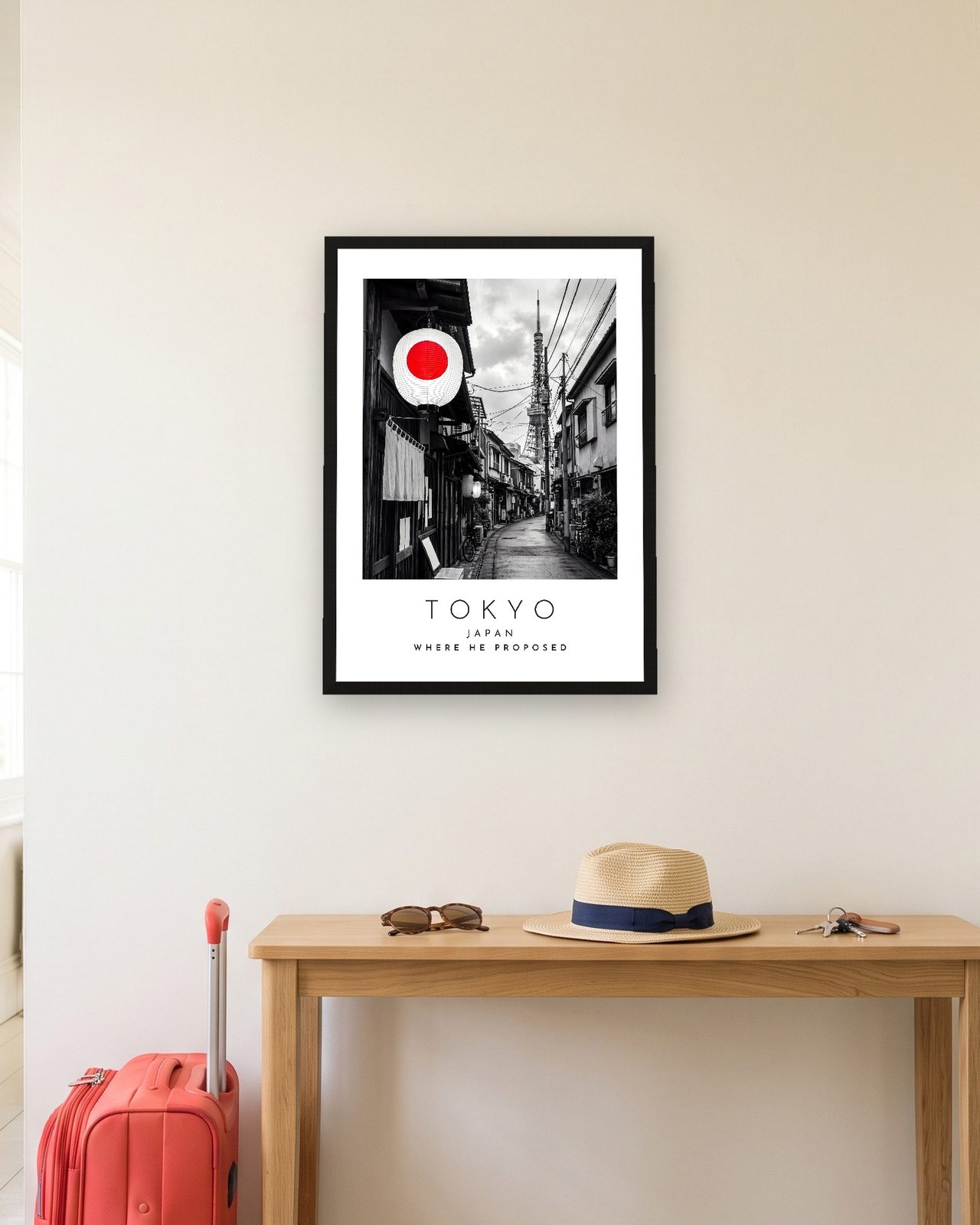Our Trip Tokyo print: black frame A3 in a hallway with a packed suitcase, personalised WHERE HE PROPOSED