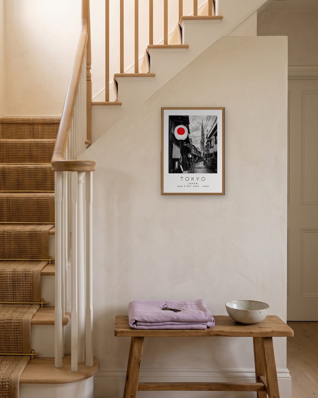 Our Trip Tokyo print: natural oak frame A3 on a staircase wall, personalised OUR FIRST TRIP · 2023