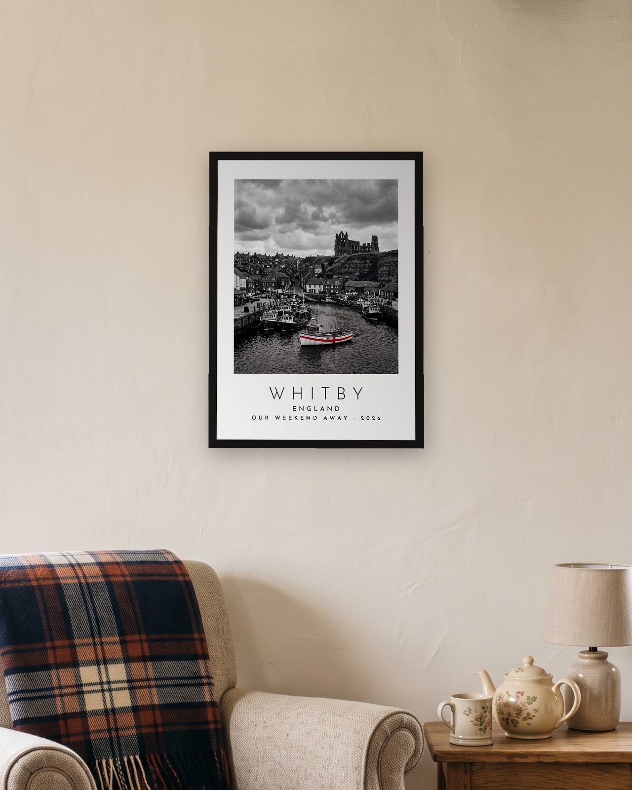 Our Trip Whitby print: black frame A3 in a cottage snug, personalised OUR WEEKEND AWAY · 2026
