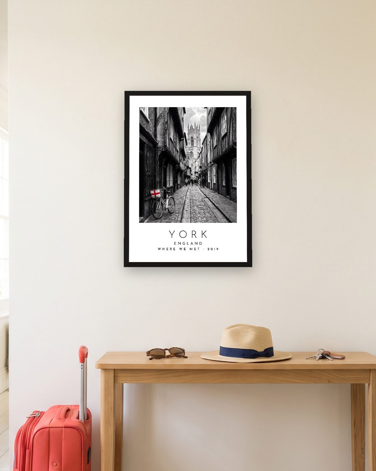 Our Trip York print: black frame A3 in a hallway with a packed suitcase, personalised WHERE WE MET · 2019