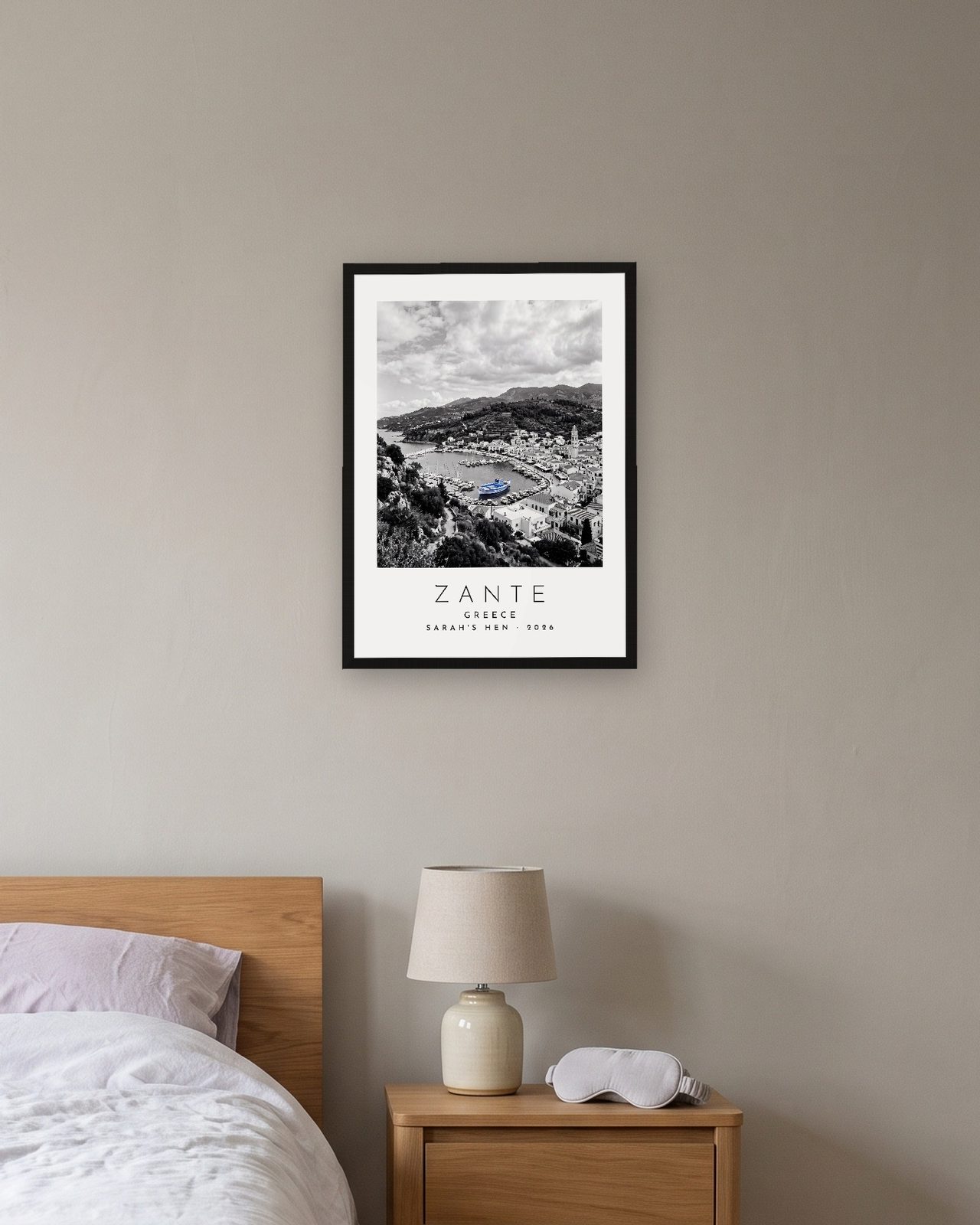 Our Trip Zante print: black frame A3 above a bedside table, personalised SARAH'S HEN · 2026